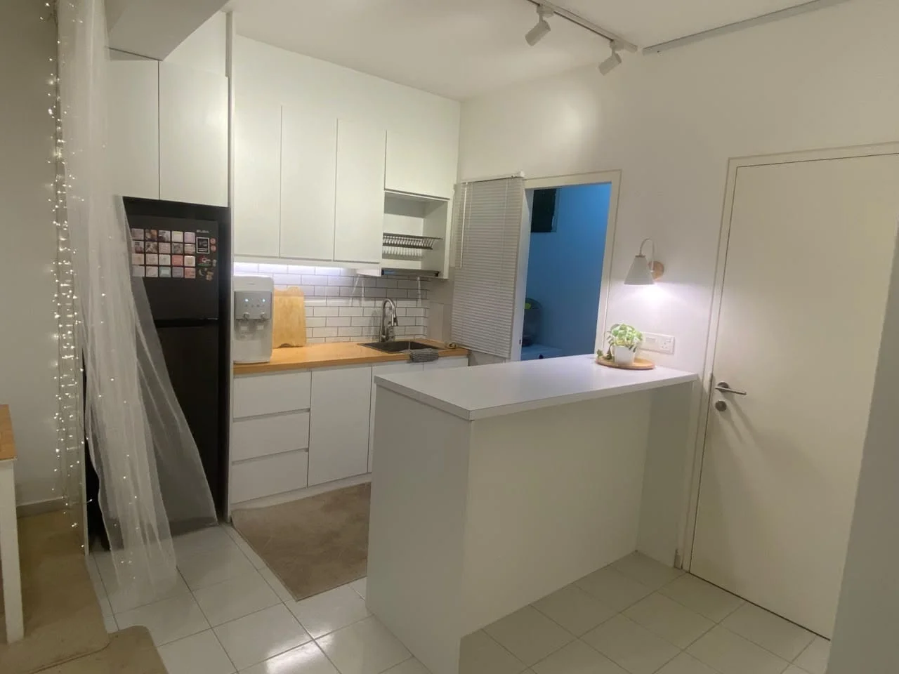 Kitchen features: white cabinetry, stainless-steel fridge, built-in oven, ceramic tile flooring, white subway tile backsplash, single-bowl stainless-steel sink, chrome pull-down faucet, wood countertop, recessed downlights, open shelving, kitchen island with seating, wall-mounted cabinets; style: modern.